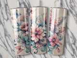 Three floral and butterfly patterned tumblers on a marble background.