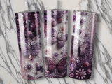 Three tumblers with purple butterfly and floral designs on a marble background.