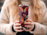Tumbler with colorful butterfly and floral design held by hands.