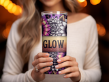 Woman holding a floral patterned tumbler with "GLOW" text.