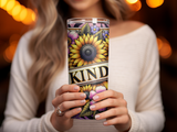 Woman holds tumbler with sunflowers and the word "Kind".