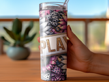 Floral patterned tumbler with "PLAY" text held by a hand.