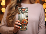 Woman holding a tumbler decorated with pumpkins, fall leaves, and poppies.