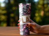 Hand holding a tall tumbler with abstract floral and geometric patterns.