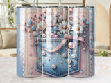 Denim pocket with flowers, pearls, and pink ribbon on a textured background.