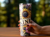 Tall tumbler with sunflowers and "KIND" text held by a hand.