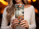 Woman holding white pumpkin and floral decorated tumbler.