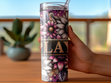 Tumbler with floral design and the word "PLAY" held by a hand.