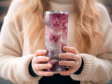 Pink glitter tumbler with butterflies and flowers held by a person.