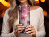 Pink butterfly design tumbler held by person wearing white sweater.