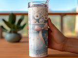 Denim tumbler with pearls and floral design, held by a woman's hand.