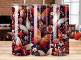A tumbler with a dark background featuring orange, red, and white butterflies and flowers.