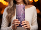 Purple tumbler with butterfly and floral design held by a woman.