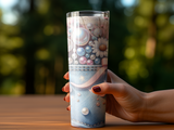 Denim tumbler with pearl and floral embellishments held by a hand.
