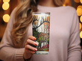 Woman holding a tumbler with a deer and forest design, "Hunting Season" text.