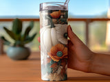 White pumpkin, poppy, and plaid tumbler with a straw held in a hand.