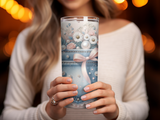 Woman holding a tall tumbler decorated with denim, pearls, and flowers.