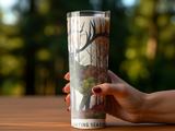 Glass tumbler with woodland scene and "Hunting Season" text held by a hand.