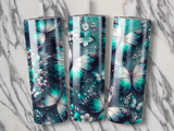 Three teal butterfly tumblers with floral and glitter patterns.