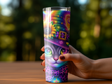 Cat wearing a witch hat with sunflower and rainbow pattern, held by a hand.