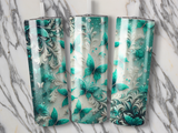 Three tumblers with teal butterflies and glitter overlay.