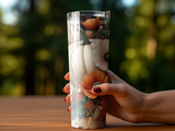 Tumbler with fall floral and pumpkin pattern held by a hand.