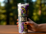 Hand holding a tall tumbler with a "BOLD" design featuring sunflowers and purple flowers.
