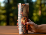Hand holding a tumbler with a fall harvest pattern.