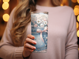 Denim tumbler with floral and pearl accents held by a woman.